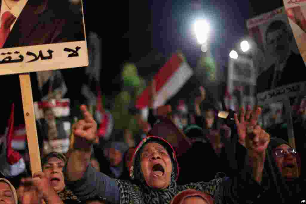 Supporters of Egypt's ousted President Mohamed Morsi chant slogans and hold posters with Arabic writing which reads "Yes for legality, No for the coup" during a protest outside Rabaah al-Adawiya mosque, Cairo, August 6, 2013. 
