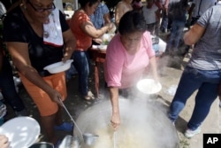 Honduran migrants who are traveling to the United States as a group get food from a a group of volunteers in Teculutan, Guatemala, Oct. 17, 2018.