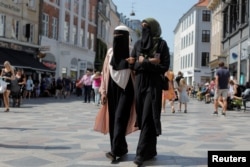 Anna-Bella (L), 26, a home care worker and Amina, 24, a student, both members of the group Kvinder I Dialog (Women in Dialogue) and wearers of the niqab, walk along Stroget, the main shopping strip in Copenhagen, Denmark, July 26, 2018.