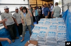 U.S. Ambassador Nikki Haley, center left, walks past food parcels provided by the World Food Program, part of the humanitarian aid shipments into Syria, during a visit at the Reyhanli border crossing with Syria, May 24, 2017.