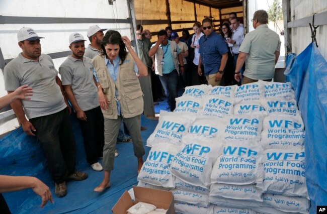 FILE - U.S. Ambassador Nikki Haley, center left, walks past food parcels provided by the World Food Program, part of the humanitarian aid shipments into Syria, during a visit at the Reyhanli border crossing with Syria, May 24, 2017.