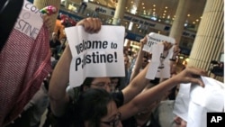 Pro-Palestinian Israeli activists hold signs during a small demonstration at the arrival terminal at Ben Gurion International Airport near Tel Aviv in support of a "fly-in" by other pro-Palestinian activists to Tel Aviv over the weekend, July 8, 2011