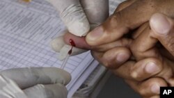 FILE - a patient undergoes a pin prick blood test inside a mobile healthcare clinic.