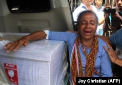 Petronela Koa menangis di sebelah peti mati yang berisi keponakannya, Adelina Sau, seorang pembantu rumah tangga yang meninggal di Malaysia, saat tiba di bandara Kupang di Nusa Tenggara Timur pada 17 Februari 2018. (Foto: AFP/Joy Christian)