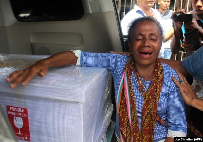 Petronela Koa menangis di sebelah peti mati yang berisi keponakannya, Adelina Sau, seorang pembantu rumah tangga yang meninggal di Malaysia, saat tiba di bandara Kupang di Nusa Tenggara Timur pada 17 Februari 2018. (Foto: AFP/Joy Christian)
