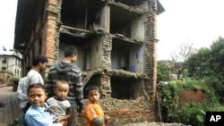 Nepalese children and other people stand near the debris of collapsed buildings damaged by an earthquake that shook northeastern India on Sunday night, in Katmandu, Nepal, September 19, 2011.