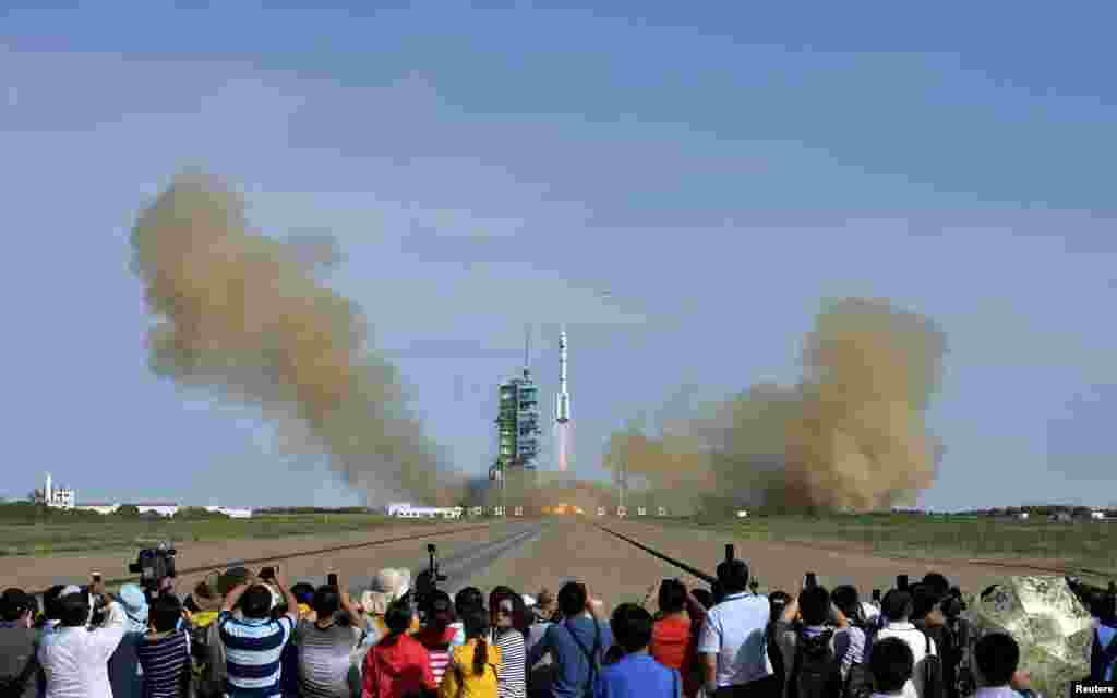 Warga menyaksikan peluncuran roket Long March 2-F yang ditunggangi pesawat luar angkasa berawak Shenzhou-10 dari landasan di Pusat Peluncuran Satelit Jiuquan, provinsi Gansu (11/6).