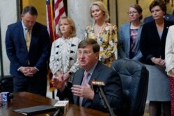 Mississippi Gov. Tate Reeves explains to reporters why he signed the first state bill in the U.S. this year to ban transgender athletes from competing on female sports teams, Thursday, March 11, 2021, at the Capitol in Jackson, Miss.