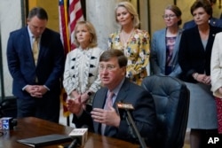 Mississippi Gov. Tate Reeves explains to reporters why he signed the first state bill in the U.S. this year to ban transgender athletes from competing on female sports teams, Thursday, March 11, 2021, at the Capitol in Jackson, Miss.