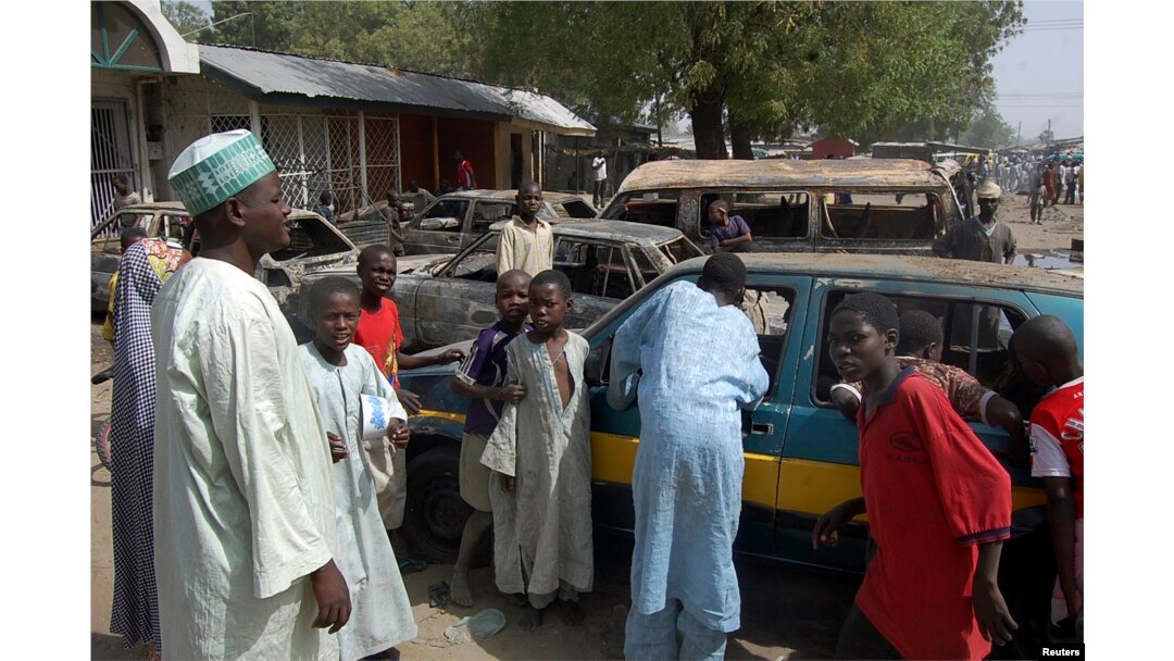 Residents survey vehicles damaged after a bomb blast at a primary school in Maiduguri, the capital of Nigeria's Borno state, February 29, 2012.