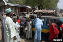 Residents survey vehicles damaged after a bomb blast at a primary school in Maiduguri, the capital of Nigeria's Borno state, February 29, 2012.