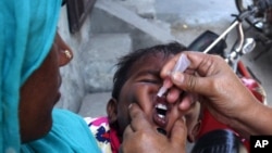 A Pakistani health worker gives a child a polio vaccine in Lahore, Pakistan, Monday, May 5, 2014.