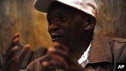 Burundi's main opposition leader Agathon Rwasa sits underneath the portrait of Burundian President Pierre Nkurunziza during an interview with journalists in the south western Burundian town of Rumonge, 12 May 2010