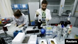 FILE - Technicians Ilya Podolsky and Natalia Bochkaryova work at the Russian anti-doping laboratory in Moscow, Russia, May 24, 2016.