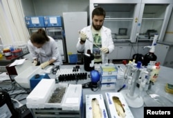 FILE - Technicians Ilya Podolsky and Natalia Bochkaryova work at the Russian anti-doping laboratory in Moscow, Russia, May 24, 2016.