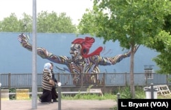 Women walk by graffiti in Grigny, which boasts 89 different nationalities.