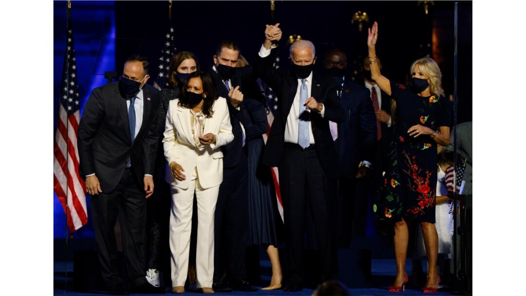 Calon presiden AS dari Partai Demokrat 2020 Joe Biden mengangkat tangan putranya Hunter, saat mereka dan calon wakil presiden Kamala Harris dan keluarga mereka merayakan di atas panggung saat kampanye. (Foto: Reuters / Jim Bourg)