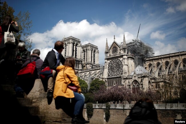 People look at Notre-Dame Cathedral two days after a massive fire devastated large parts of the gothic structure in Paris, Apr. 17, 2019.