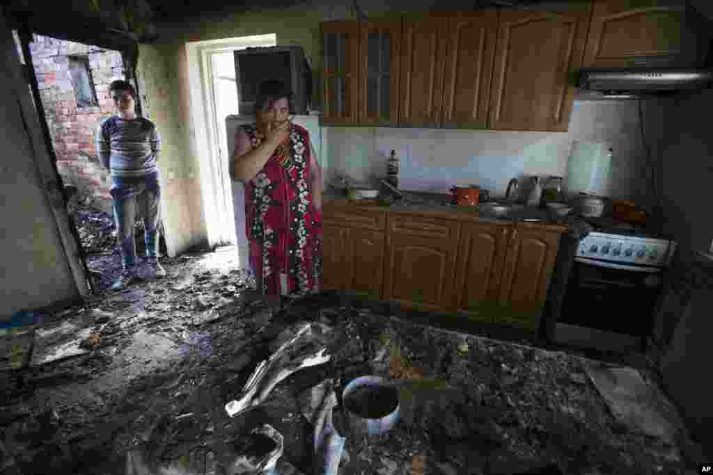 Yekaterina Len, 61, center, cries inside the remains of her house damaged by shellfire as her grandson stands near her, in Slovyansk, eastern Ukraine, May 20, 2014.