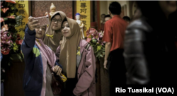 Tiga perempuan berhijab berfoto di kawasan Pecinan Bandung dalam tur Malam Imlek 2018 yang digelar Jaringan Kerja Antar-umat Beragama (Jakatarub) sejak 2013. (Foto: Kharisma Prima/Bandung Lautan Damai)