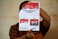 Seorang petugas menunjukkan surat suara saat melakukan perhitungan hasil Pilpres di sebuah TPS di Jakarta, Rabu 17/4.
