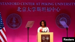U.S. first lady Michelle Obama gives a speech next to American (L) and Chinese national flags at the Peking University in Beijing, March 22, 2014. 