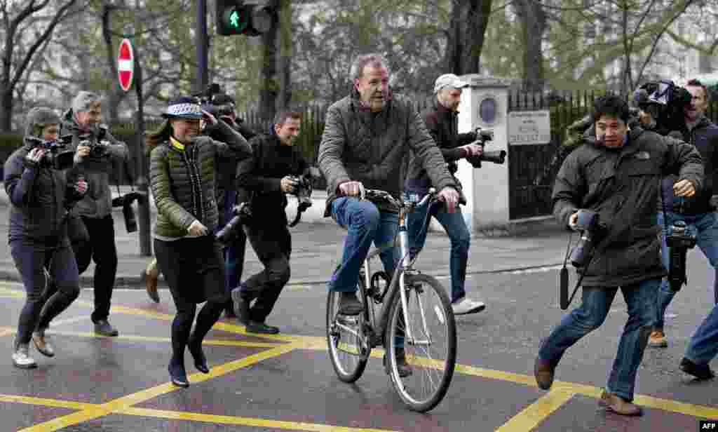 British television presenter Jeremy Clarkson (C) is surrounded by media personnel as he leaves his home on a bicycle in London. The BBC announced that it was dropping one of its most popular presenters, "Top Gear" host Jeremy Clarkson, for physically attacking a producer.