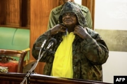 Uganda's President Yoweri Museveni dons a jacket with a hoot, explaining to motorbike taxi drivers how not to wear them, as he gives a state of security address during a special session of the Parliament in Kampala on June 20, 2018.