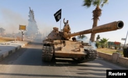 FILE - Militant Islamist fighters on a tank take part in a military parade along the streets of northern Raqqa province.