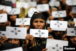 FILE - Rohingya refugee women hold placards as they take part in a protest at the Kutupalong refugee camp to mark the one-year anniversary of their exodus from Myanmar, in Cox's Bazar, Bangladesh, Aug. 25, 2018.
