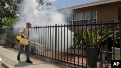 A Miami-Dade County mosquito control worker sprays around a home in the Wynwood area of Miami on Aug. 1, 2016. 