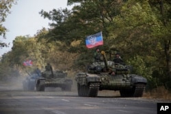 FILE - Russia-backed rebels' tanks, with a flag of the self-proclaimed Donetsk People's Republic, are seen near Novoazovsk, eastern Ukraine, Oct. 21, 2015.