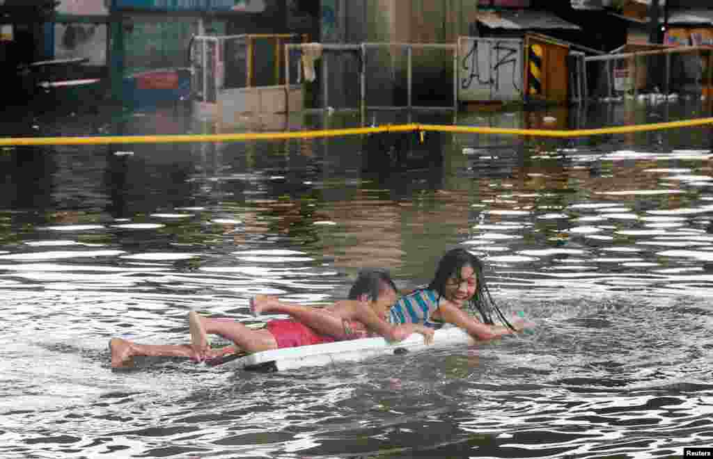 Children use a makeshift raft as they play along a partially flooded street caused by monsoon rains and Tropical Storm Son-Tinh in Quezon city, Metro Manila, in Philippines, July 17, 2018.