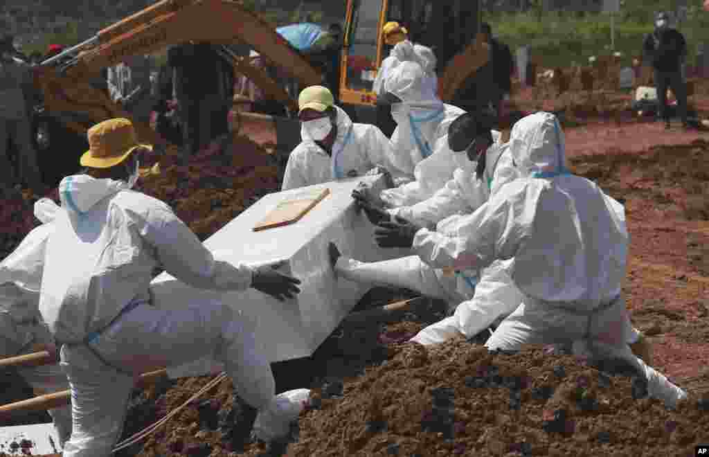 Workers in protective gear lower a coffin of a COVID-19 victim for burial at the special area of the Pedurenan cemetery created to keep up with the rise in deaths during the coronavirus outbreak in Bekasi, West Java, Indonesia.