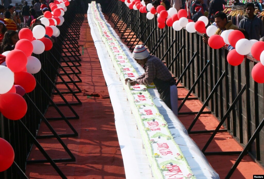 A man decorates a 210 feet-long (64 meters) cake during Christmas celebrations at a consumer fair in Chandigarh, India, Dec. 25, 2017.