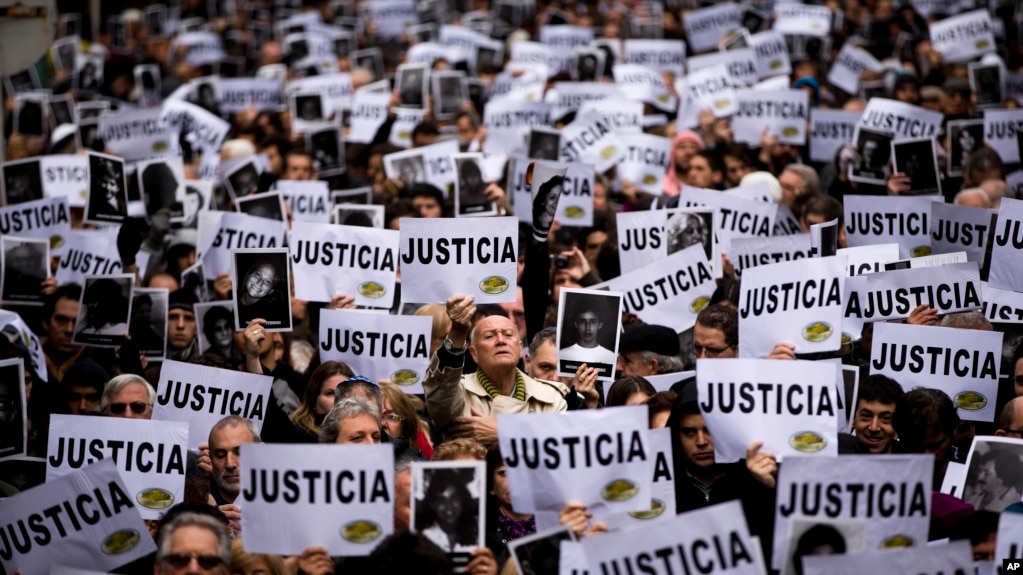 تجمع مردمی که با در دست داشتن تصاویر قربانیان بمب‌گذاری «آمیا» خواستار اجرای عدالت هستند – بوئنوس آیرس، آرژانتین ژوئیه ۲۰۱۳ 