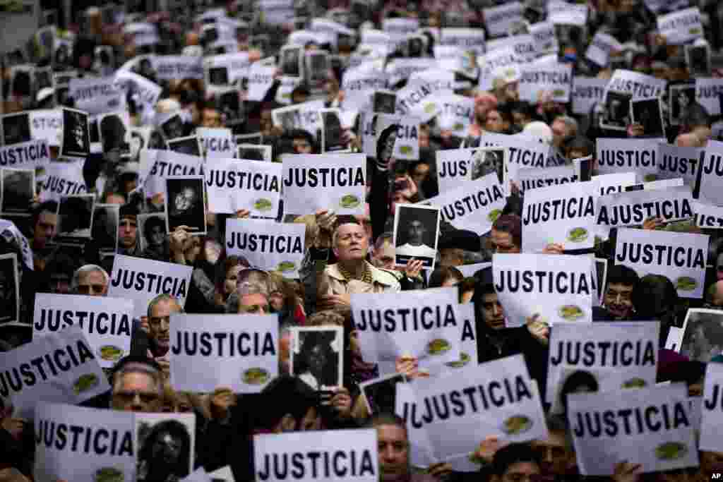 People hold up signs that read in Spanish "Justice," and photos of the victims of the bombing of the AMIA Jewish community center on the 19th anniversary of the terrorist attack in Buenos Aires, Argentina. The bombing of the Argentine-Israeli Mutual Association killed 85 people in 1994 and remains unsolved.