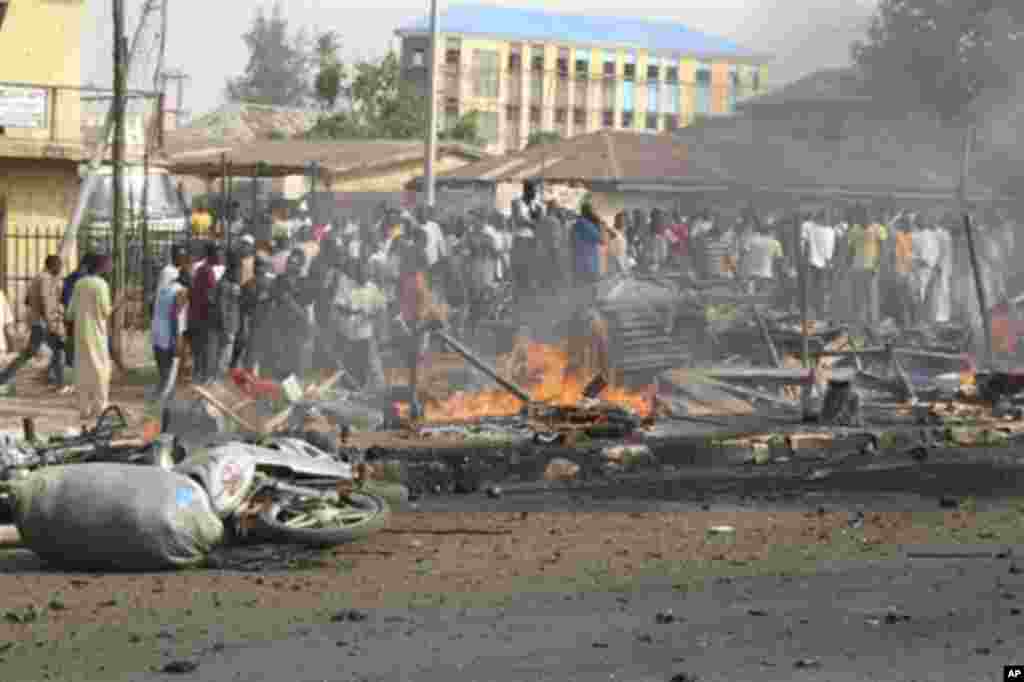 Nan mutane ne 'yan kallo suka taru a inda Bom ya fashe a hanyar Kaduna, Nigeria lahadin da ta gabata, 8 ga watan nan na Afilu, 2012.