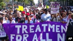 FILE - Activists march in Durban, South Africa, July 18, 2016, at the start of the 21st World AIDS Conference to demand that funds not be cut in the fight against HIV/AIDS. Eight years later, great progress has been made in the battle, but dwindling funding remains an issue.