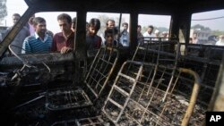 FILE - People look at the burned remains of a passenger vehicle on the outskirts of Srinagar in Indian-controlled Kashmir, Oct. 17, 2016. Kashmir is witnessing the largest protests against Indian rule in recent years, sparked by the July 8 killing of a popular rebel commander by Indian soldiers.