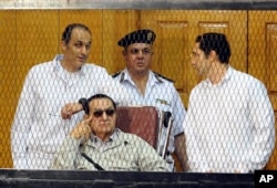FILE - former Egyptian president Hosni Mubarak, seated, and his two sons Gamal Mubarak (L) and Alaa Mubarak (R) are seen attending a hearing in a Cairo courtroom Sept. 14, 2013.