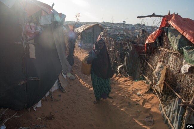 FILE - A girl carries a baby boy in a camp in Kismayo, Somalia that is home to both displaced Somalis and returned refugees on September 27, 2016. (J. Patinkin/VOA)