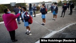 Un enseignant vérifie la température des élèves alors que les écoles commencent à rouvrir après dans le canton de Langa au Cap, en Afrique du Sud, le 8 juin 2020.
