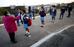Seorang guru memeriksa suhu tubuh para murid di sekolah yang mulai buka kembali setelah lockdown terkait pandemi Covid-19 dicabut, di Kota Langa, Cape Town, Afrika Selatan, 8 Juni 2020.