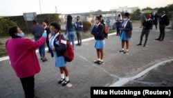 Une enseignante prend la température de chaque élève avant la classe dans le canton de Langa au Cap, Afrique du Sud le 8 juin 2020. (REUTERS/Mike Hutchings)