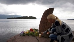 FILE - A woman lights a candle at a makeshift memorial to victims of bombing and shooting attacks by right-wing terrorist Anders Breivik, opposite Utoya island, Norway, July 24, 2011.