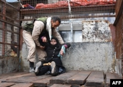 A wounded Syrian woman from the al-Sukari neighbourhood is helped onto the back of a truck as she flees during the ongoing government forces military operation to retake remaining rebel-held areas in the northern embattled city of Aleppo on December 14, 2