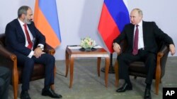 Armenian Prime Minister Nikol Pashinian (L) listens to Russian President Vladimir Putin during their meeting in the Black Sea resort of Sochi, Russia, May 14, 2018.