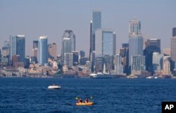 Kayakers and boaters ply the waters of Elliott Bay with the Seattle skyline behind during a heat wave hitting the Pacific Northwest, Sunday, June 27, 2021. (AP Photo/John Froschauer)