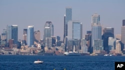 Kayakers and boaters ply the waters of Elliott Bay with the Seattle skyline behind during a heat wave hitting the Pacific Northwest, Sunday, June 27, 2021. (AP Photo/John Froschauer)